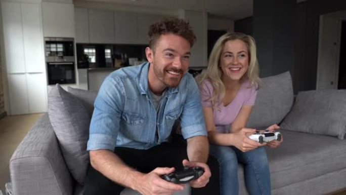 快乐的年轻夫妇在家里玩电子游戏竞争非常兴奋