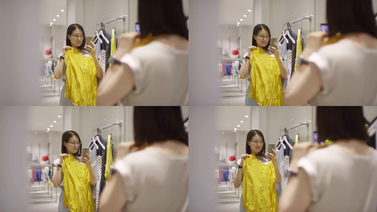 中国妇女在试衣间的镜子里用智能手机自拍