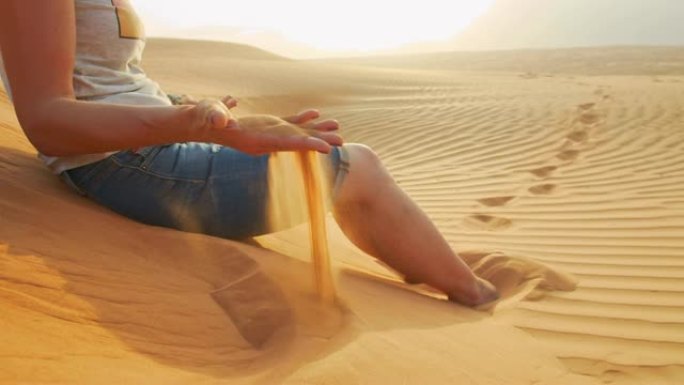 女士坐在沙丘上，慢动作