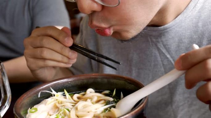 滚动手持男子吃乌冬面，日本面条