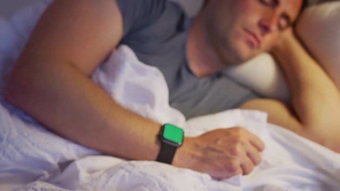 相机放大了戴着智能手表睡在床上的男人