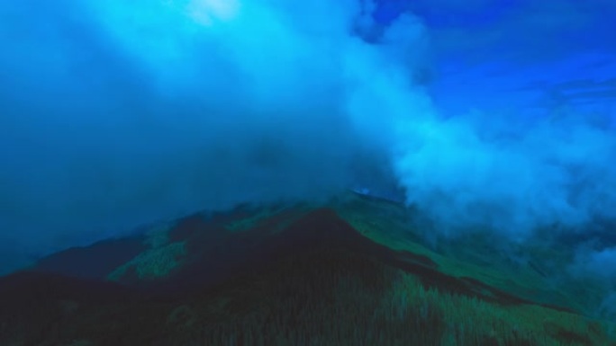 在蓝色云流背景下的山上飞行。过度下垂