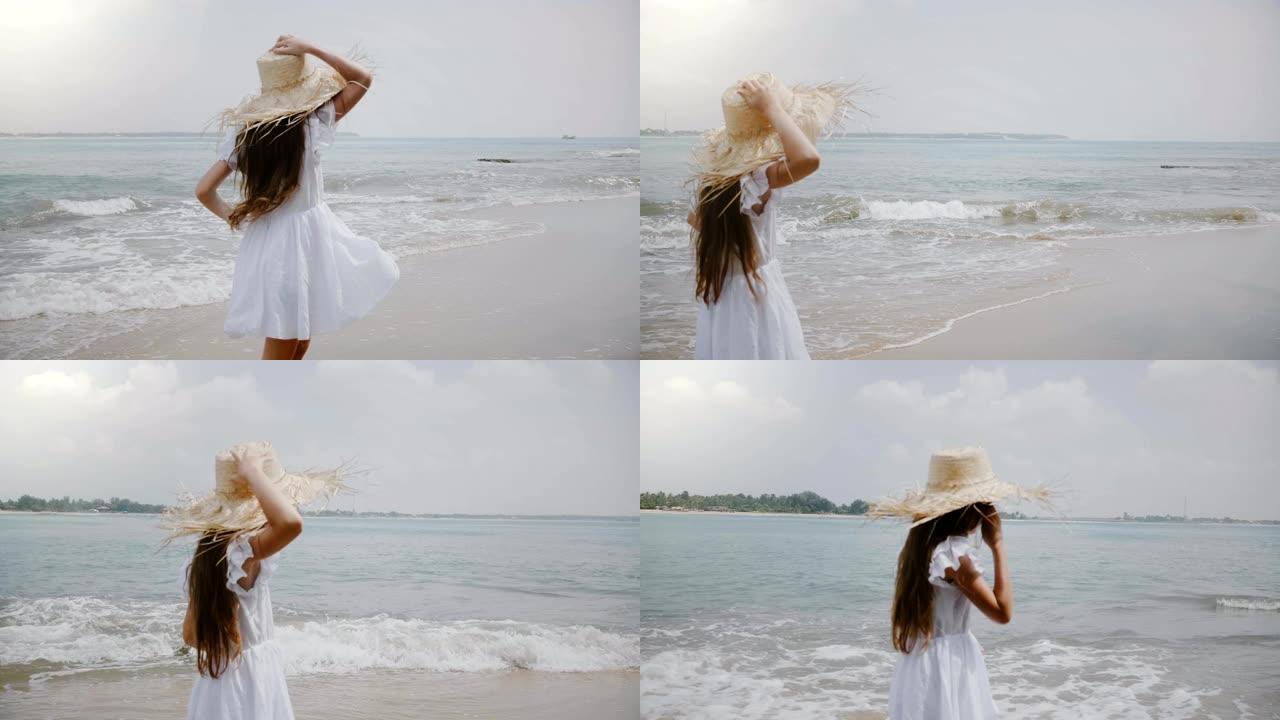 快乐美丽的5-7岁女孩，留着飞舞的头发，戴着大草帽，沿着电影般的热带异国海洋海滩奔跑