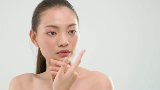 亚洲妇女用美容护肤产品摩擦皮肤在白色的背景。