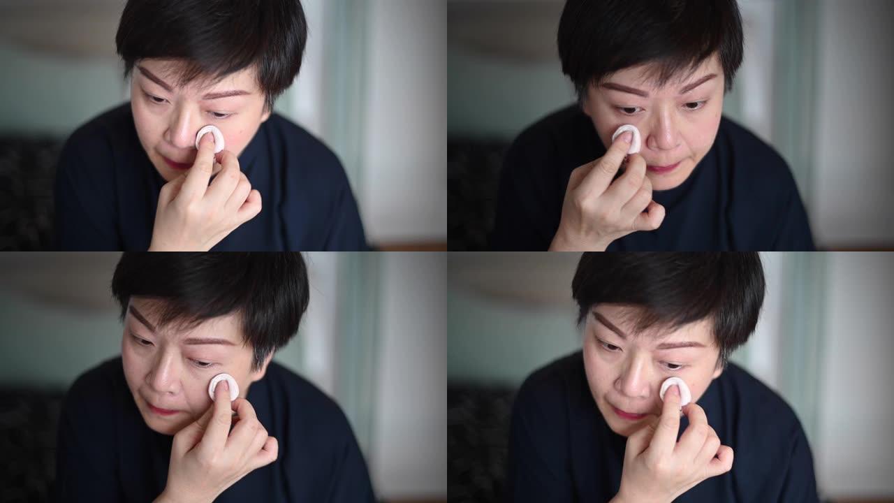 一名亚洲中国中年成年人在离开公寓前准备化妆，画眉毛