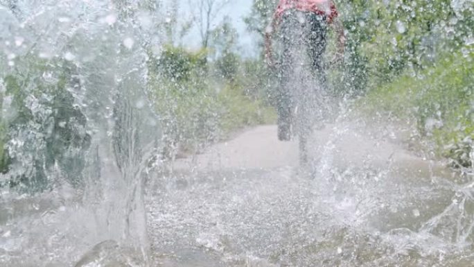 SLO MO (实时慢速) 骑自行车的人在土路上跳入水坑