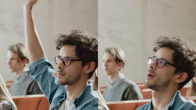 英俊的西班牙裔学生在大学里使用笔记本电脑听力讲座，举手问讲师一个问题。多民族学生群体。垂直屏幕方向9