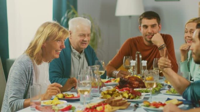 家人和朋友聚集在餐桌上。高级夫妇聊天、开玩笑和吃饭。老人和年轻人开怀大笑。