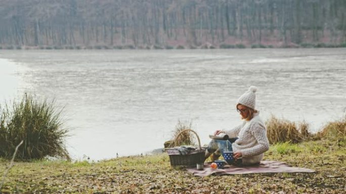 女士在斯洛文尼亚Prekmurje宁静的秋季湖畔喝热咖啡