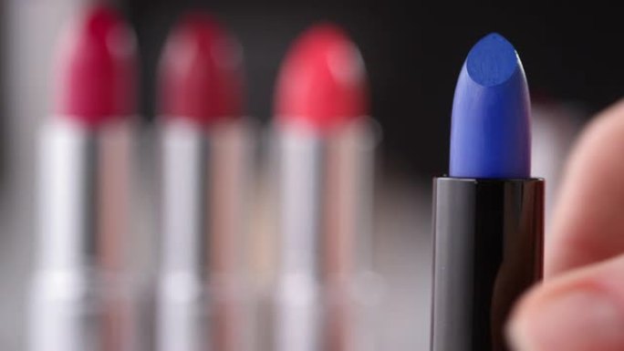 女性手在化妆台上扭动蓝色唇膏