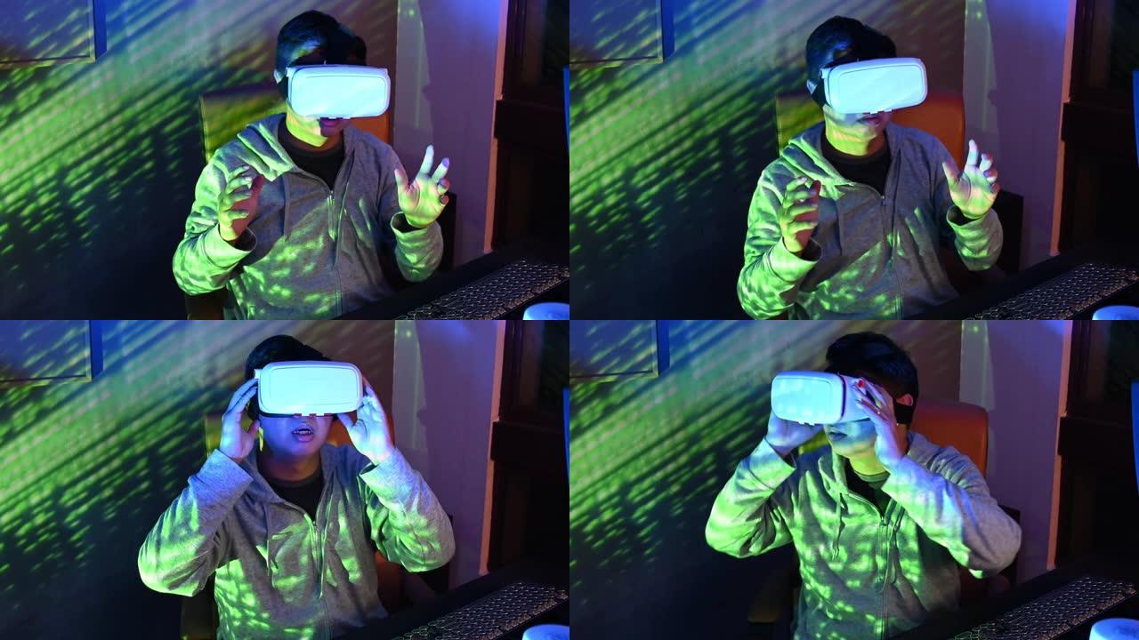 一位亚洲华裔男性晚上在自己的家庭办公室书房里，在台式机前戴上VR护目镜并体验3D虚拟游戏体验