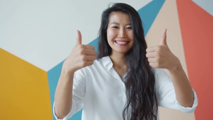 快乐的亚洲女商人的肖像用双手竖起大拇指