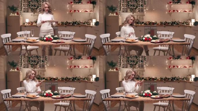 一个漂亮的金发女郎正在为客人的到来准备圣诞晚餐。她在家里的厨房里摆了一张喜庆的桌子。