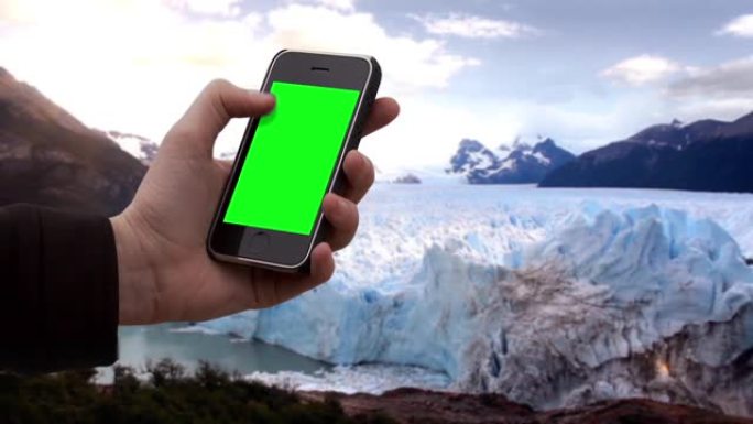 男性手在冰川中使用智能手机绿屏。