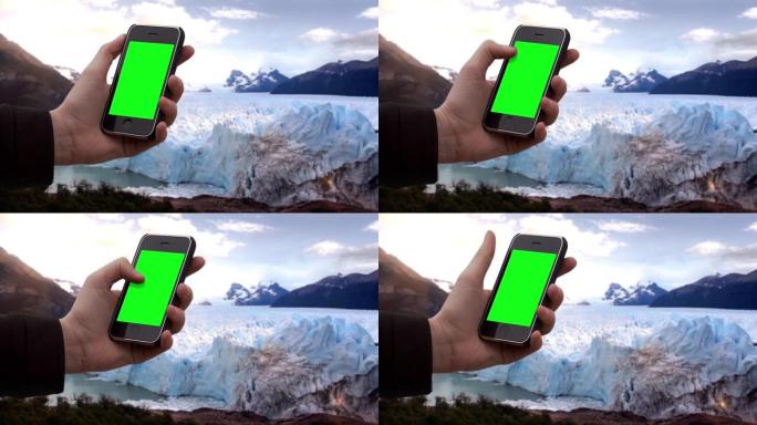 男性手在冰川中使用智能手机绿屏。