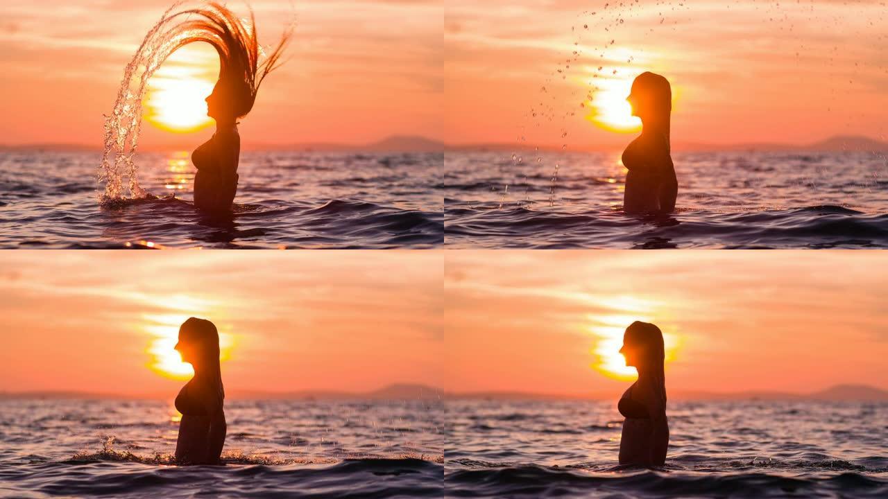 热带度假的女人在日落时分在海洋中泼水长发