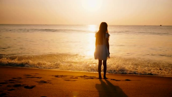 在史诗般的金色海洋海滩上，快乐的小女孩观看令人难以置信的日落，触摸温暖的海浪。