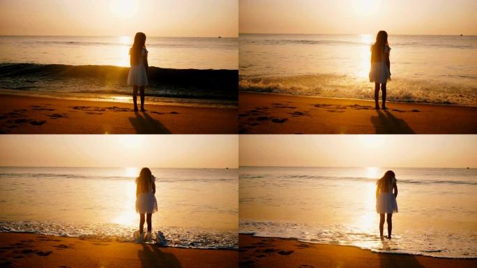 在史诗般的金色海洋海滩上，快乐的小女孩观看令人难以置信的日落，触摸温暖的海浪。