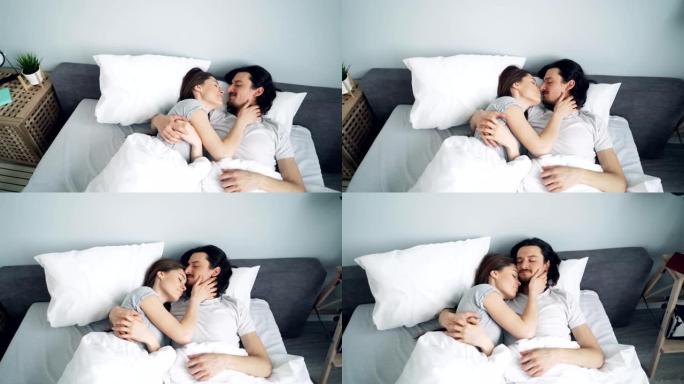 可爱情侣拥抱亲吻然后睡在家里的床上的高角度视图