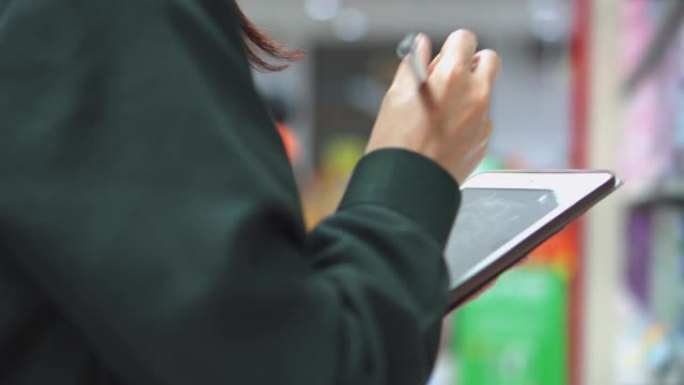 在超市中使用数字平板电脑检查产品的女售货员