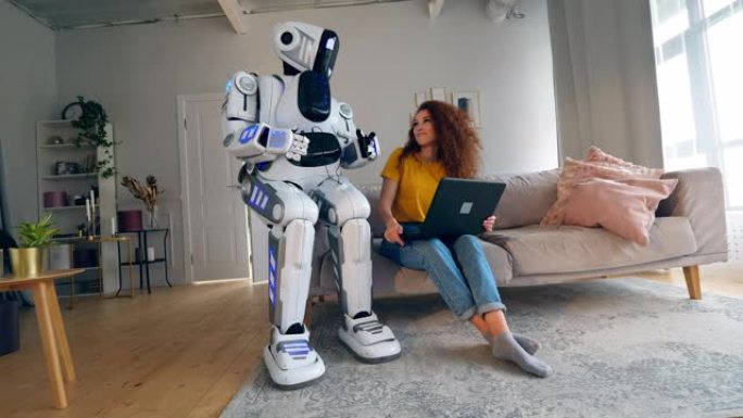 机器人、半机械人与人类概念。一个女孩和一个半机械人在房间里用笔记本电脑工作。