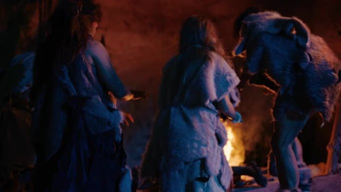 尼安德特人或智人家庭在篝火上煮动物肉，然后食用。史前狩猎采集者部落穿着动物皮烧烤，晚上在山洞里吃肉
