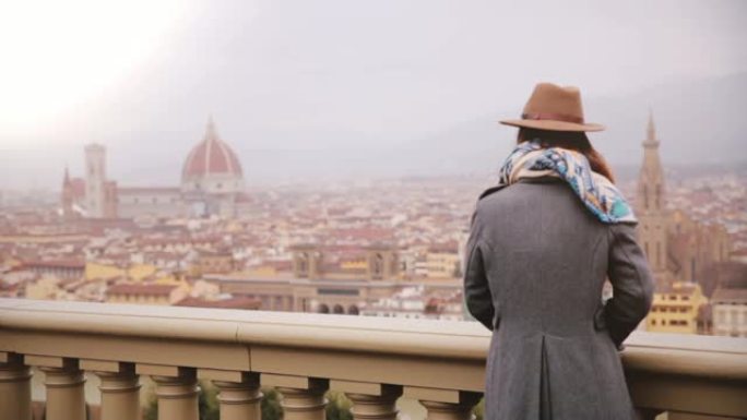站在观景台上的帽子女孩的后视图，在寒冷的阴天欣赏意大利佛罗伦萨的壮丽景色。