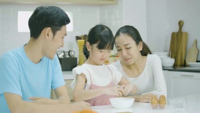 微笑的亚洲父亲、母亲和女儿喜欢一起在厨房准备健康的晚餐。母亲教女儿做饭。