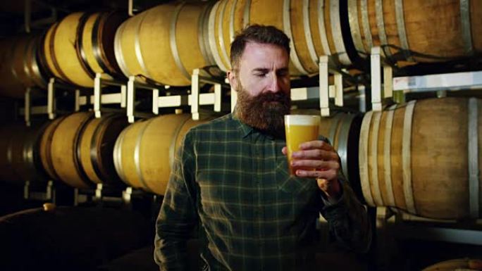 酿酒师专家从以前用于调味葡萄酒或啤酒的木桶中检查新鲜啤酒的质量。对啤酒和葡萄酒的热情。旧的和传统的工