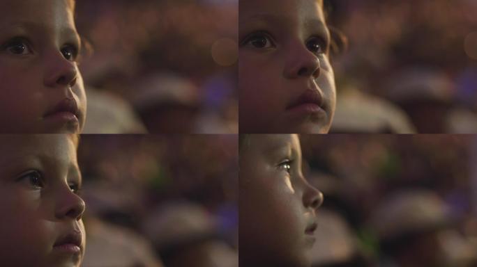 一个小女孩的脸的特写镜头，用灯光效果观看节目。