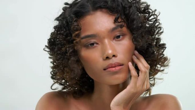 非洲妇女用白色背景上的美容护肤产品摩擦皮肤。
