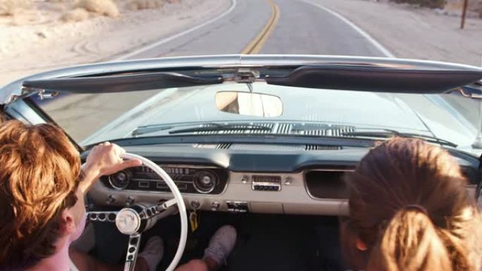 年轻的白人夫妇驾驶敞开式汽车，后视图