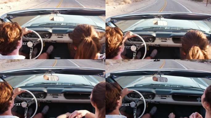 年轻的白人夫妇驾驶敞开式汽车，后视图