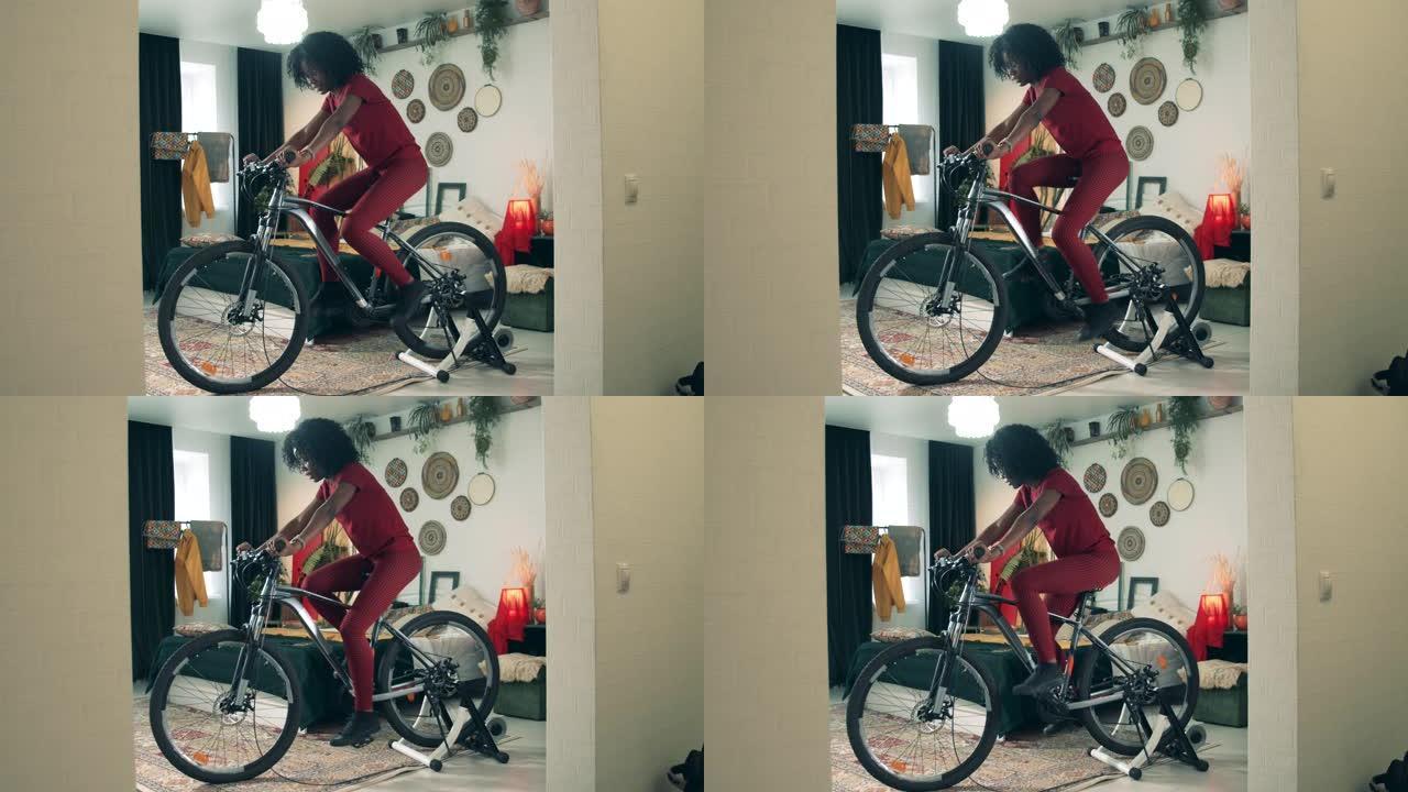 在家运动，在家健身。非裔美国女士正在家里的健身机上骑自行车