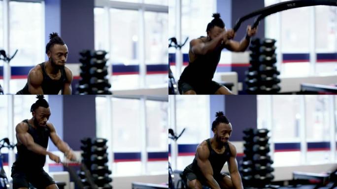一位强壮的成年男性正在健身房内进行激烈的绳索锻炼