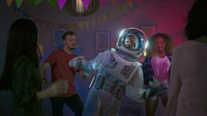 在大学服装派对上: 穿着太空服的有趣家伙跳舞，做机器人舞蹈现代动作。和他一起美丽的女孩和男孩在霓虹灯