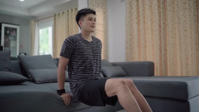 亚洲男子在客厅在线教程的帮助下在家锻炼。