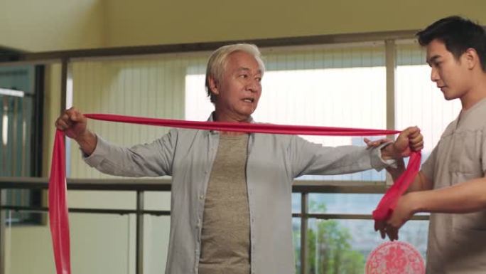 年轻的亚洲物理治疗师与高级患者一起工作