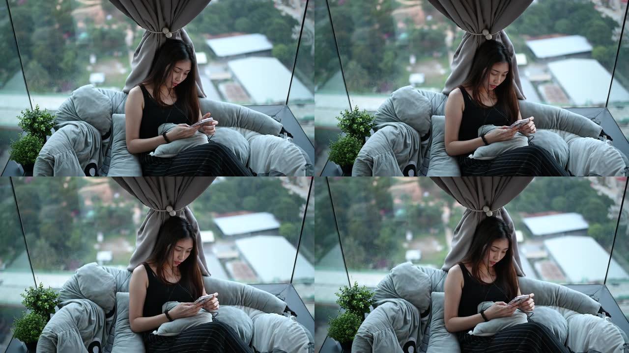 一名亚洲华裔年轻女子在公寓拐角处用手机听音乐