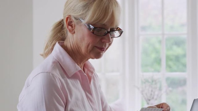 成熟的女人在家使用笔记本电脑在线查找药物信息