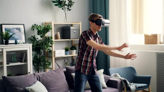年轻人在虚拟现实眼镜上玩游戏，站在家里戴着设备和移动的手。