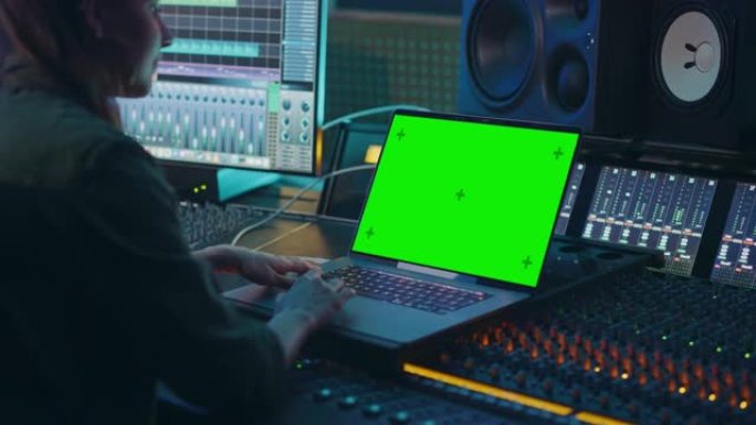 女艺术家，音乐家，制作人，音频工程师在音乐唱片公司的新专辑中工作，使用绿屏笔记本电脑，控制台进行混音