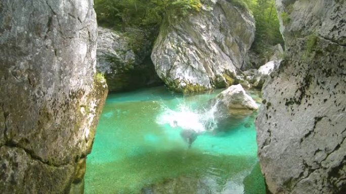 慢动作: 兴奋的人从一块大石头上跳下来，进入绿松石色的索卡河。