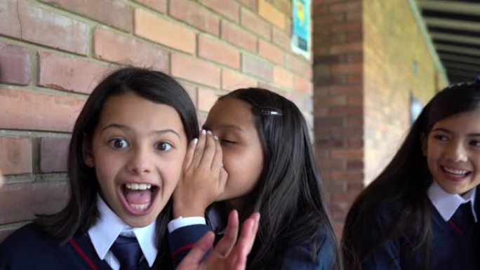 拉丁美洲女孩在学校讲秘密，看起来很开心