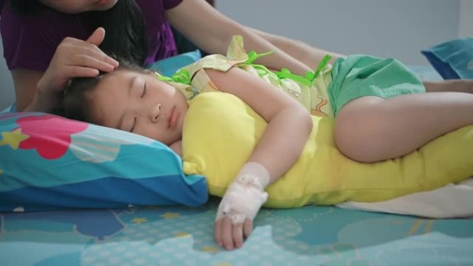 生病的小女孩在医院睡觉，母亲在医院抚摸女儿的头。