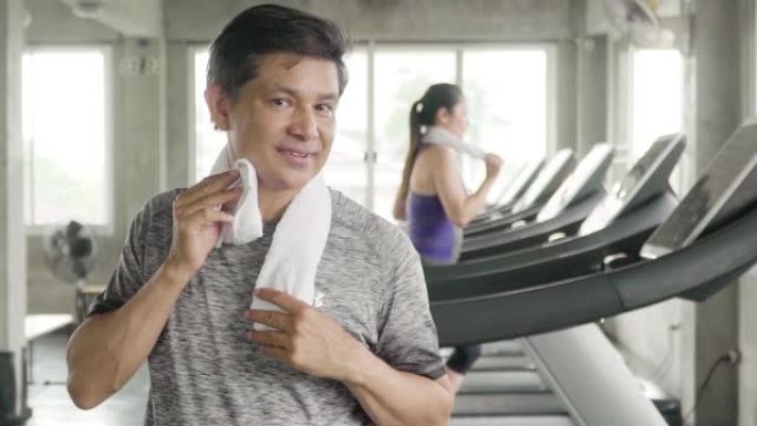 微笑的男人在健身房用餐巾纸擦汗