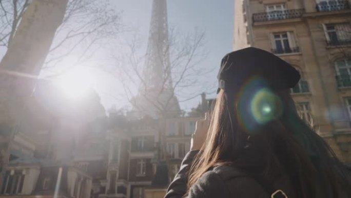 快乐美丽的旅游女人在巴黎度假时拍摄艾菲尔铁塔的智能手机照片，惊人的镜头闪光慢动作。