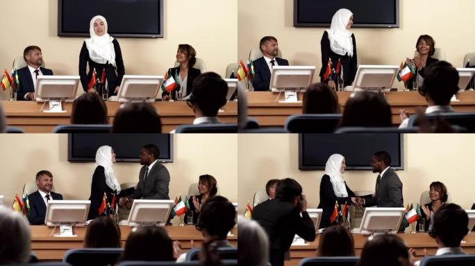 穆斯林妇女在大会上发言并与黑人同事握手