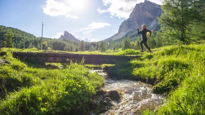 女运动员在大自然的户外慢跑，在水旁的绿色景观中
