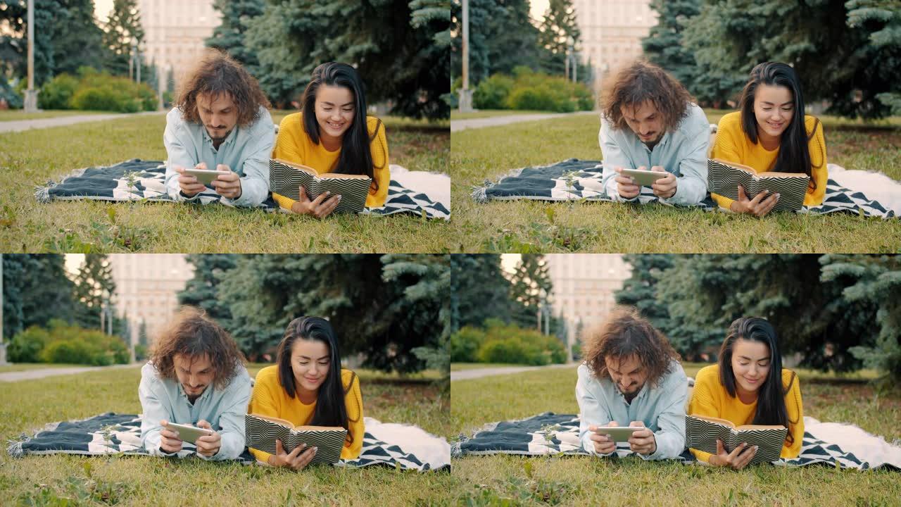 男人在玩智能手机游戏，而女人在城市公园外面看书